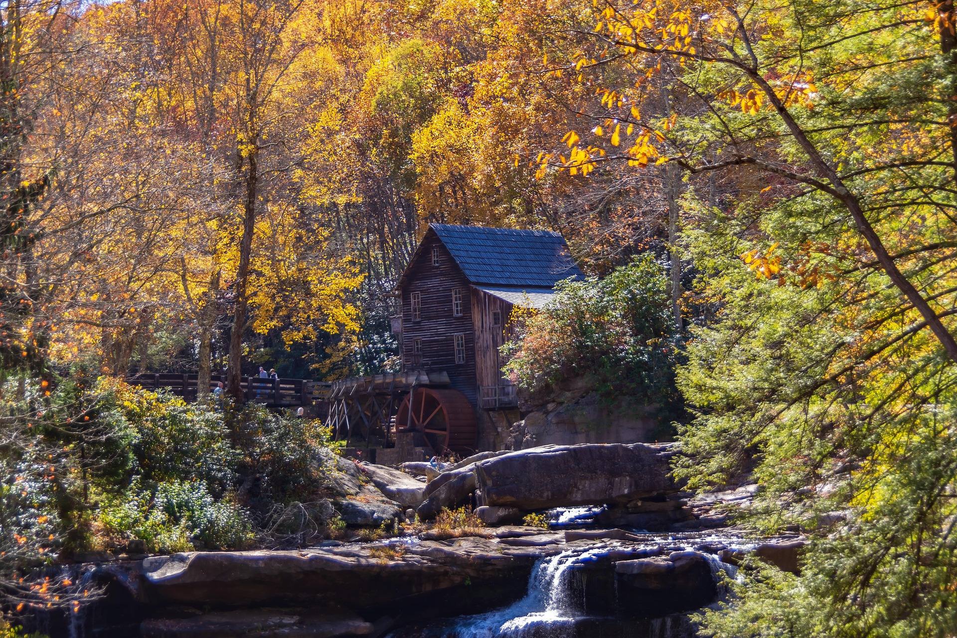 Glade Creek Grist Mill at Babcock State Park framed by peak fall foliage above a rocky creek