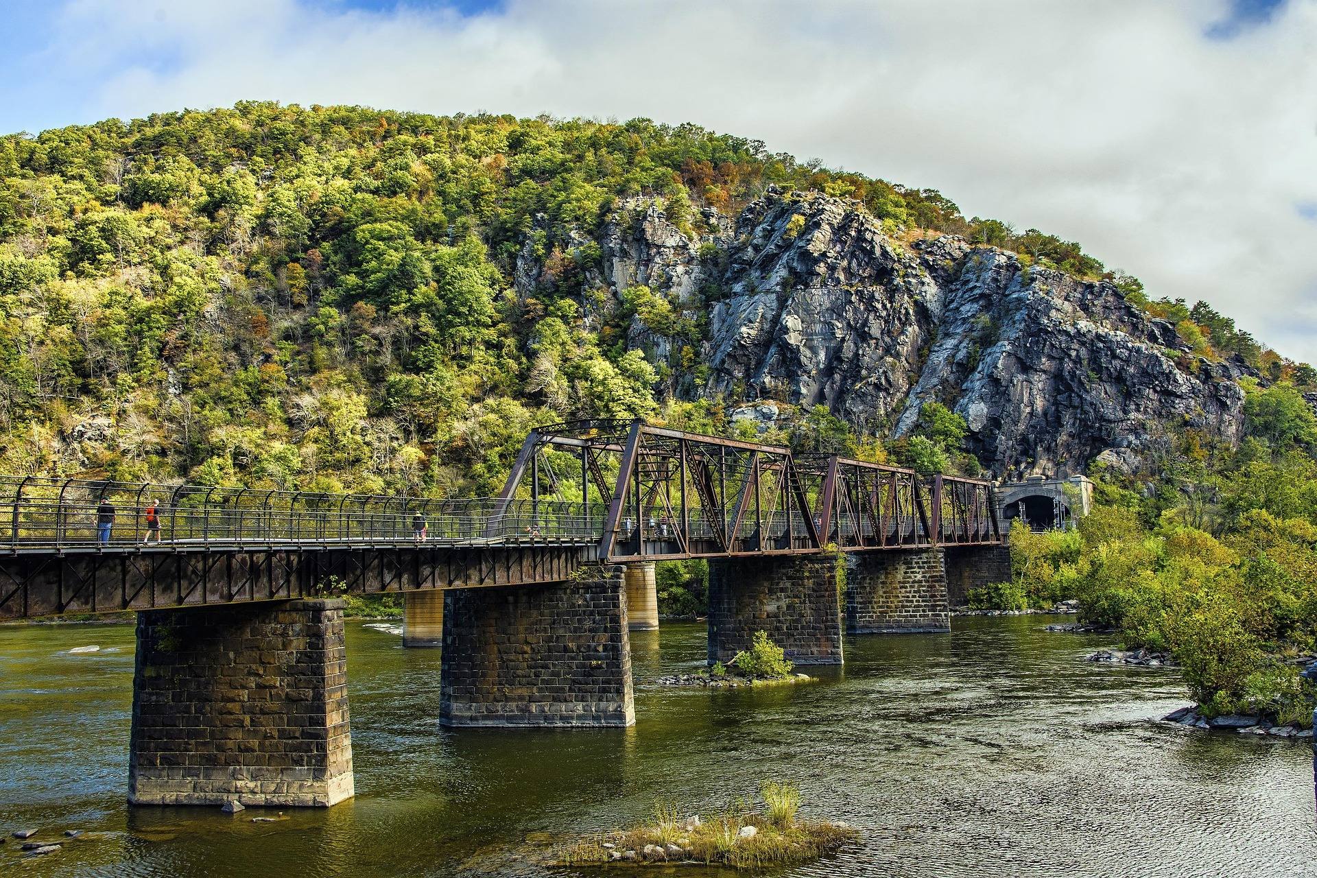 A stone-pier railroad bridge crossing a wide river below wooded cliffs on the Potomac in West Virginia